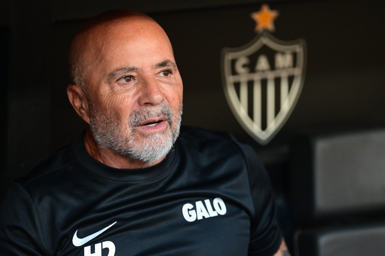 Jorge Sampaoli de camisa preta do Atlético à frente do escudo do clube (foto: Leandro Couri/EM/D.A. Press)