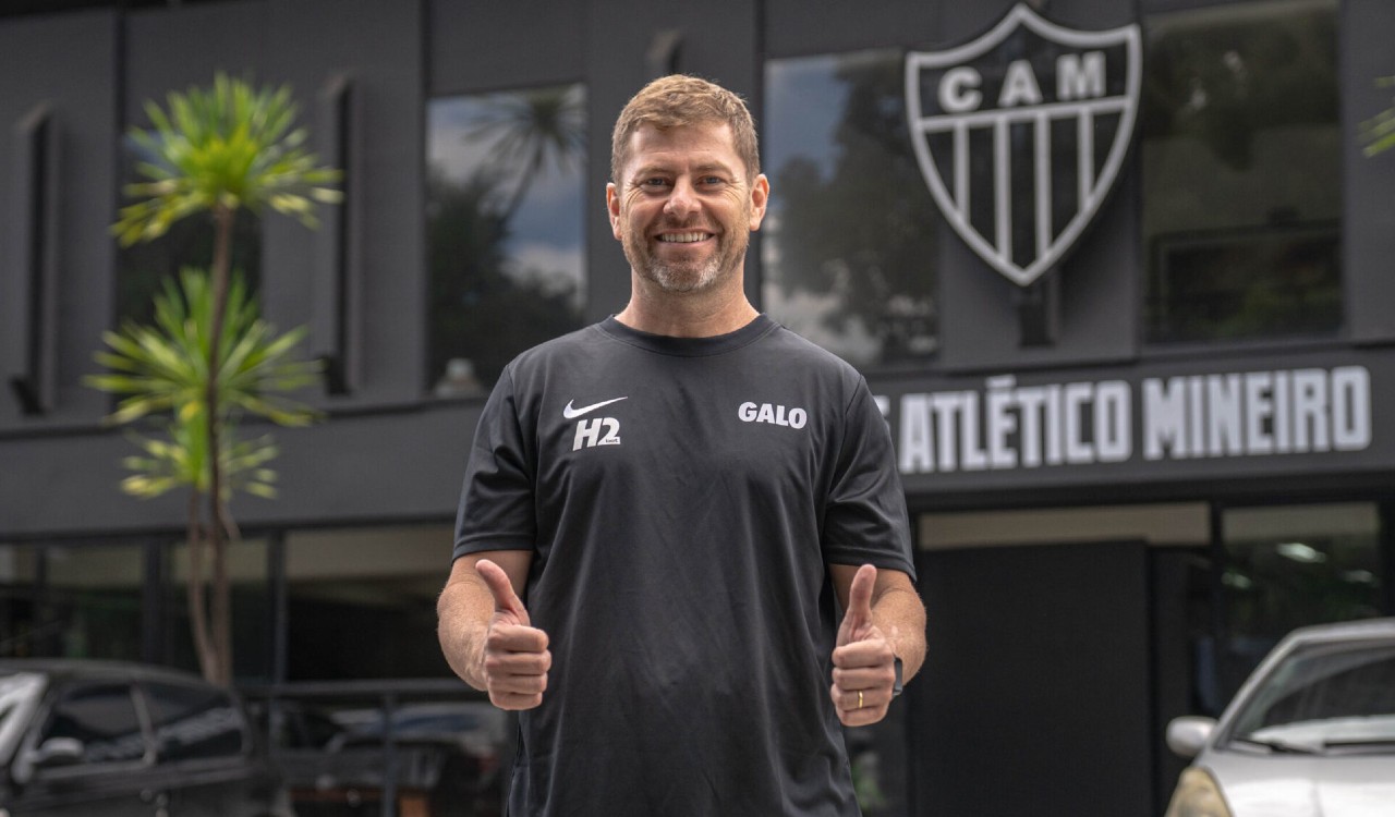 Rafael Paiva, do Atlético, de camisa preta à frente do escudo e fazendo sinal de joia com as duas mãos (foto: Fabio Pinel / Atlético)