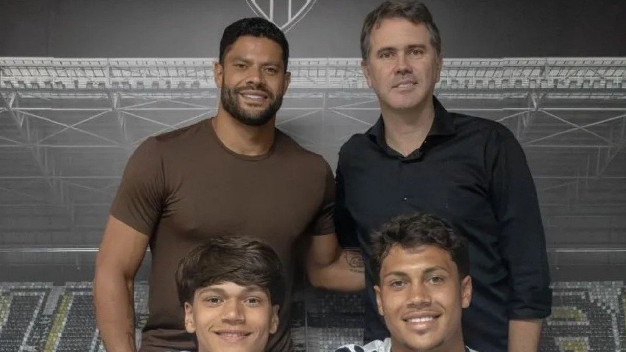 O jogador Hulk com seus dois filhos e um homem adulto sorrindo em fundo de estádio. (foto: Reprodução)
